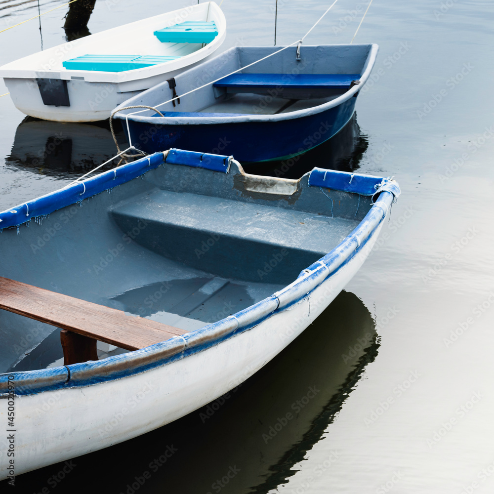 Three boats in the bay. Abstract geometry of empty dinghies on the blue seawater.