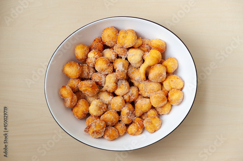 Delicious and traditional homemade Brazilian sweet called "Bolinho de Chuva" on a plate. Isolated on wooden background. Top view. Copy space.