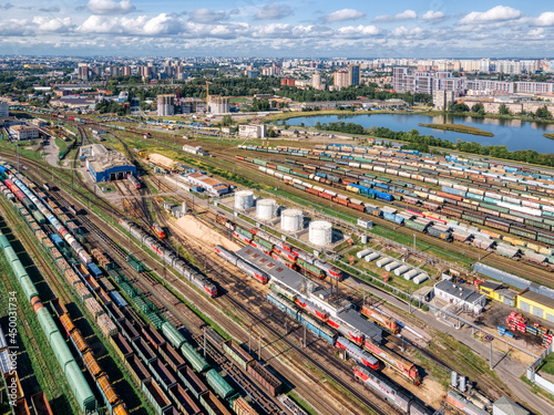 Aerial photo of railway terminal. On the railroad lots of various colorful wagons: tanks, platforms, dump trucks, dumpcars. Cargo transportation. Import and export logistics. Industrial landscape.
