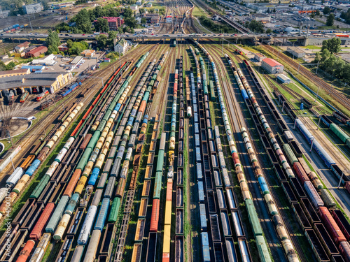 Aerial photo of lots of various wagons: tanks, platforms, dump trucks, dumpcars stay on railways at terminal. Cargo transportation of various goods by rail. Import and export logistics. photo
