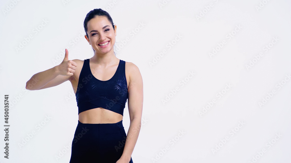 cheerful young sportswoman showing thumb up isolated on white cheerful young sportswoman showing thumb up isolated on white