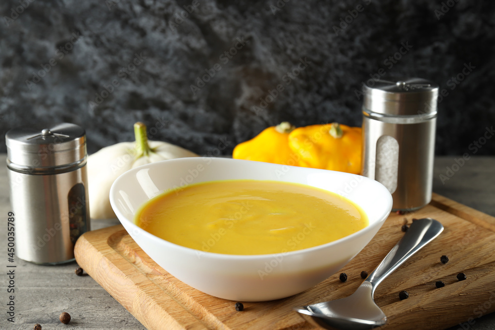 Concept of tasty food with pumpkin soup on gray textured table Concept of tasty food with pumpkin soup on gray textured table