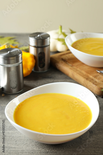 Concept of tasty food with pumpkin soup on gray textured table