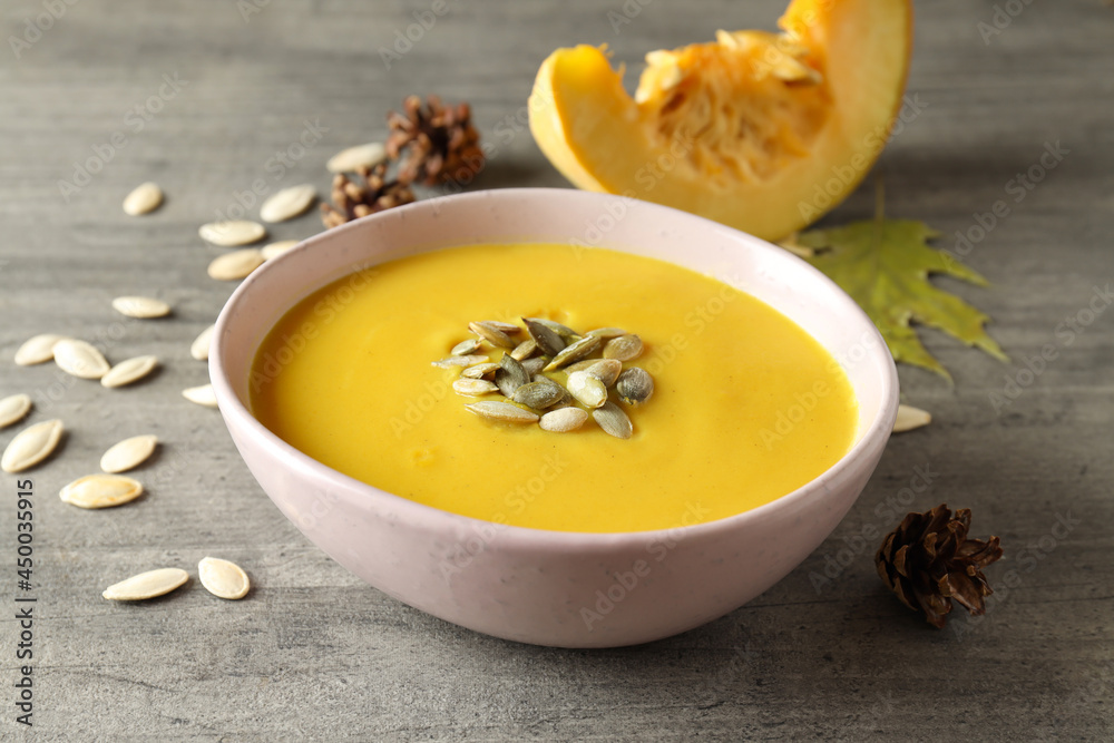 Concept of tasty food with pumpkin soup on gray textured table Concept of tasty food with pumpkin soup on gray textured table