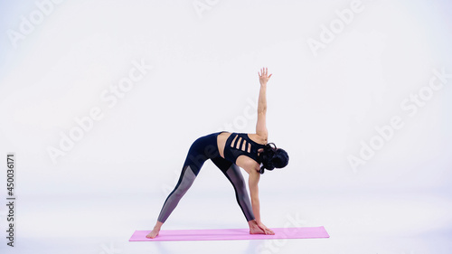 full length of young brunette woman in sportswear exercising on fitness mat on white