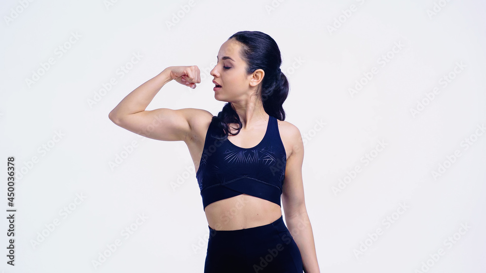 Obraz premium strong sportswoman showing muscle isolated on white