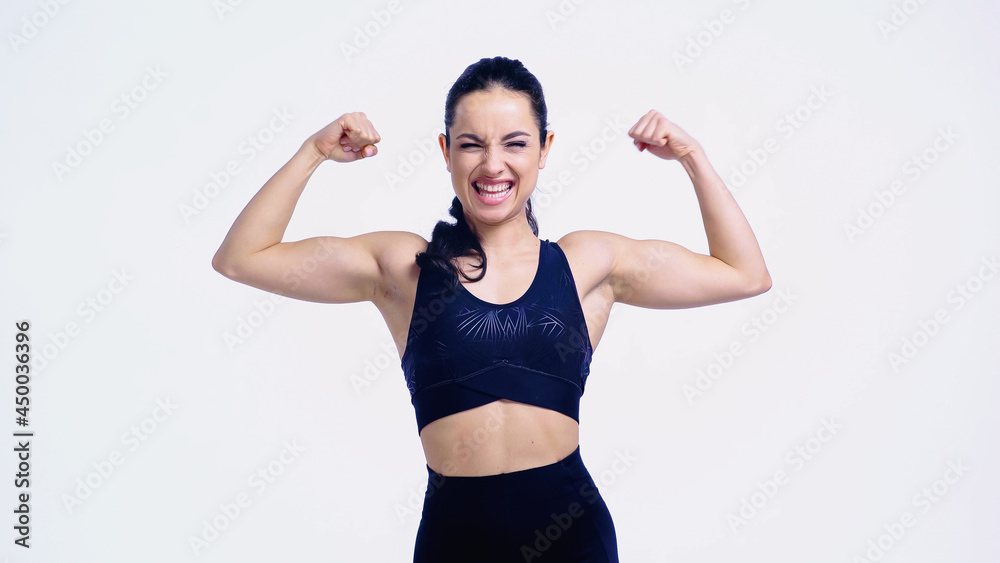 excited sportswoman showing muscles isolated on white