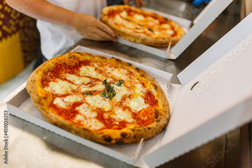 Due pizze margherita napoletane con sugo di pomodoro e mozzarella di bufala mentre vengono chiuse in due cartoni da asporto per pizze