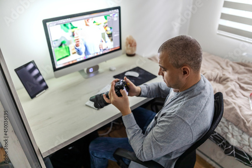 Homework corner. A close-up shot of a man employed in a media agency who controls and monitoring photos with the most modern camera Multimedia editing and improvement in home office by the male person