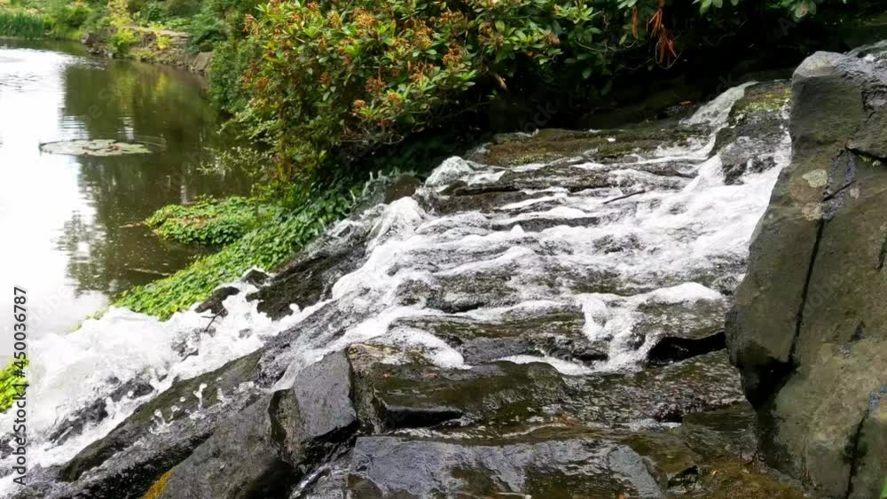On an artificial slope in the park, water flows over the stones On an artificial slope in the park, water flows over the stones