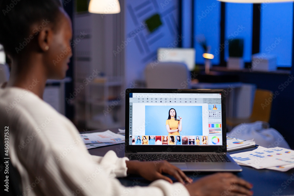 Creative african american retoucher working at design production retouching photography using editing software technology. Photographer on laptop. Woman overworking in creativity office at night Creative african american retoucher working at design production retouching photography using editing software technology. Photographer on laptop. Woman overworking in creativity office at night
