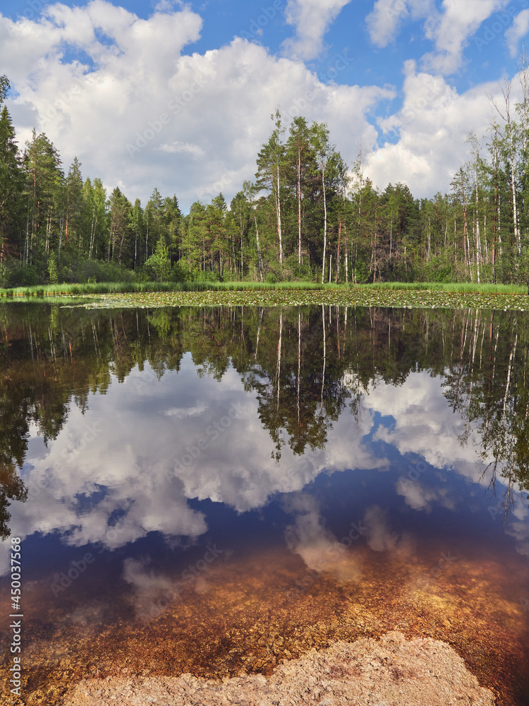 Ollilanlampi pond in Finland on a sunny summer day with clouds reflection forest and stone. Ollilanlampi pond in Finland on a sunny summer day with clouds reflection forest and stone.