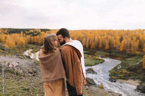 A happy couple in love in casual clothes travel together, hike and have fun in the autumn forest, enjoy nature on a weekend in fall. A man and a woman on a romantic date countryside