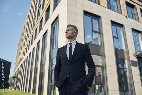 Confident mature businessman standing in front of the office building outdoors