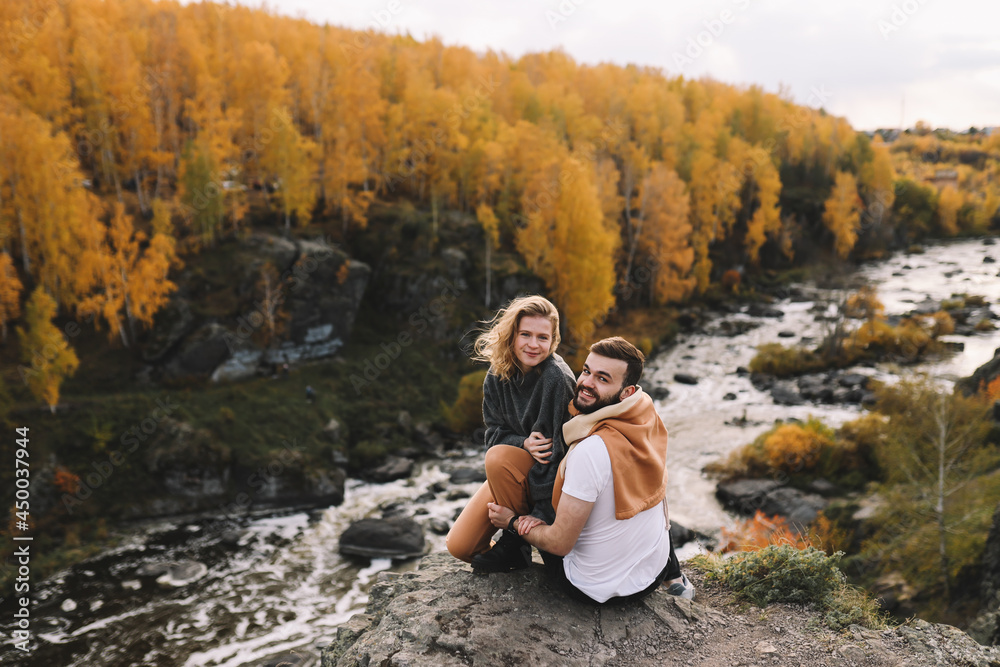 A happy couple in love in casual clothes travel together, hike and have fun in the autumn forest, enjoy nature on a weekend in fall. A man and a woman on a romantic date countryside