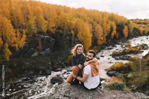 A happy couple in love in casual clothes travel together, hike and have fun in the autumn forest, enjoy nature on a weekend in fall. A man and a woman on a romantic date countryside