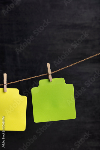 Blank green paper notes hang with clothespin on rope. Copy space. Place for your text. Black background