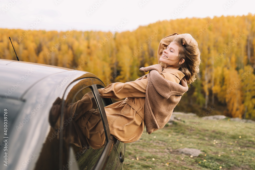 A happy pretty smiling young woman in casual warm clothes enjoys solitude drinking coffee walking traveling by car in the autumn forest in nature golden fall A happy pretty smiling young woman in casual warm clothes enjoys solitude drinking coffee walking traveling by car in the autumn forest in nature golden fall