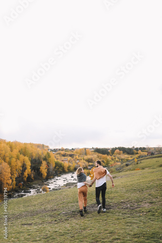 Fototapeta Naklejka Na Ścianę i Meble -  A happy couple in love in casual clothes travel together, hike and have fun in the autumn forest, enjoy nature on a weekend in fall. A man and a woman on a romantic date countryside