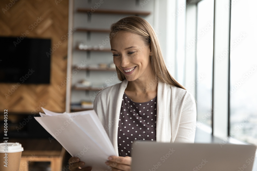 Happy business woman, office employee, assistant reviewing papers, reading documents, receiving letter with good news, contract project, approved loan bank notice, agreement. Paperwork concept Happy business woman, office employee, assistant reviewing papers, reading documents, receiving letter with good news, contract project, approved loan bank notice, agreement. Paperwork concept