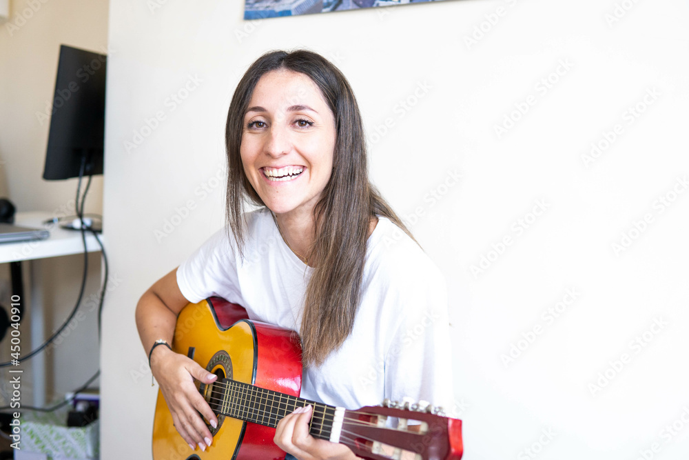 Music Concepts. Latin girl playing guitar. Latin girl relaxing with music. Latin woman have a happy lifestyle. Beautiful Latin girl playing guitar at home.