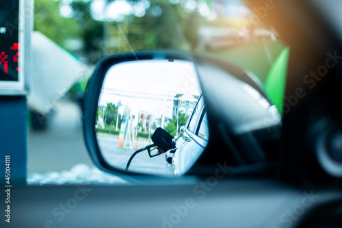 ฺBlurry image of refueling in side mirror of car. Side view mirror with  the fuel refueling service for the car. © Koonsiri