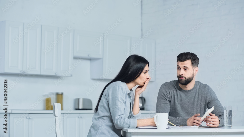 bearded man showing calculator to woman bearded man showing calculator to woman