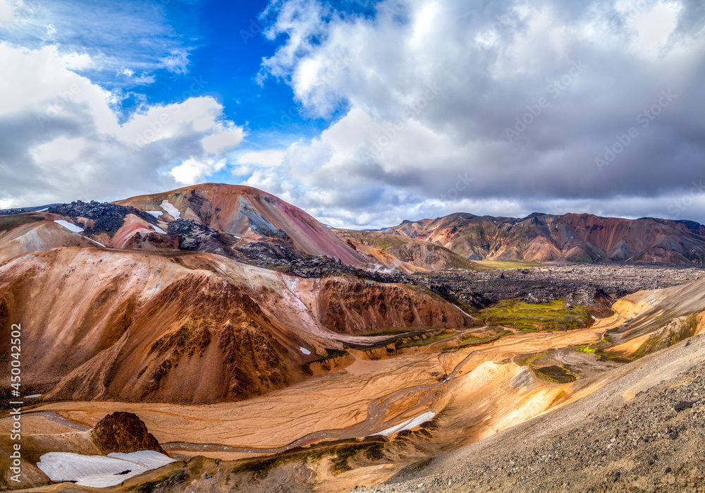 Giant orange mountain panorama under blue cloud sky at Landmannalaugar, Iceland