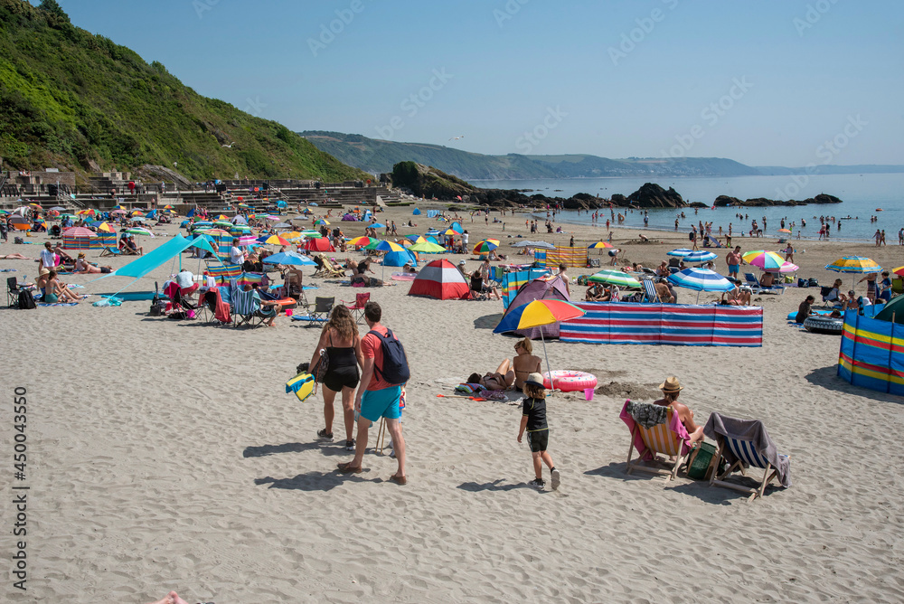 Looe, Cornwall, England, UK. 2021. Holidaymakers sunbathing on the beach at East Looe a very popular resort in Cornwall, UK. Looe, Cornwall, England, UK. 2021. Holidaymakers sunbathing on the beach at East Looe a very popular resort in Cornwall, UK.