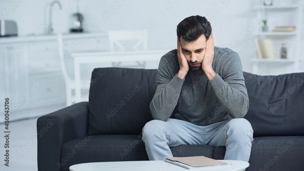 tensed man looking at folder and touching face at home tensed man looking at folder and touching face at home