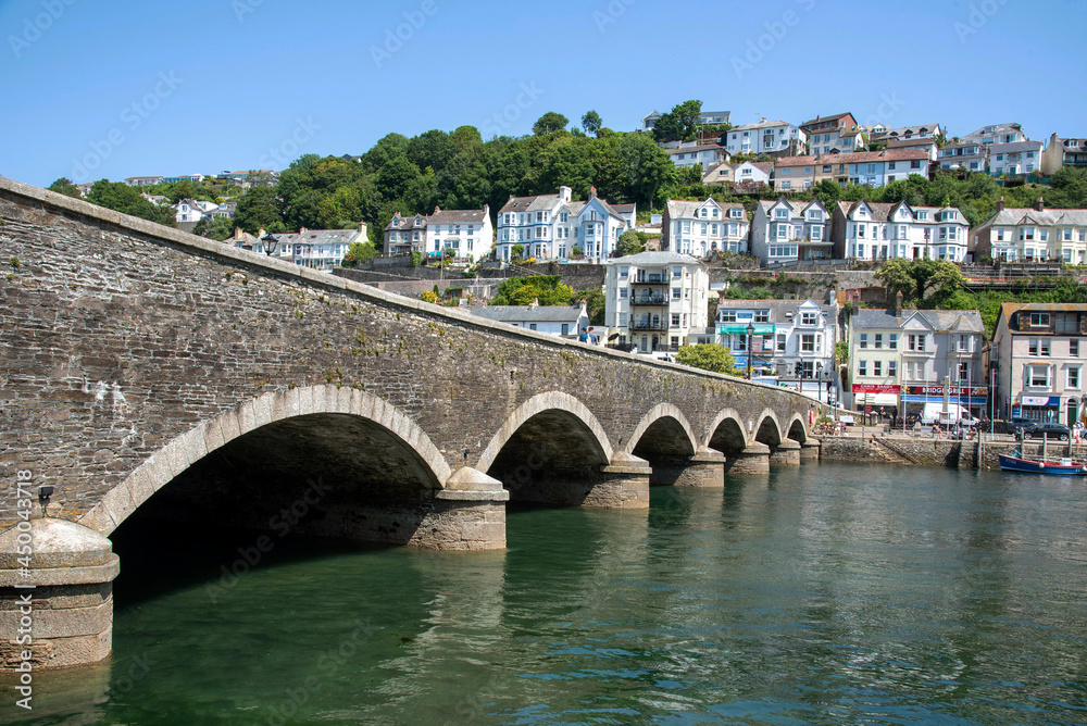 Looe, Cornwall, England, UK. 2021.  Stone road bridge crossing the tidal River Looe which devides East and West Looe