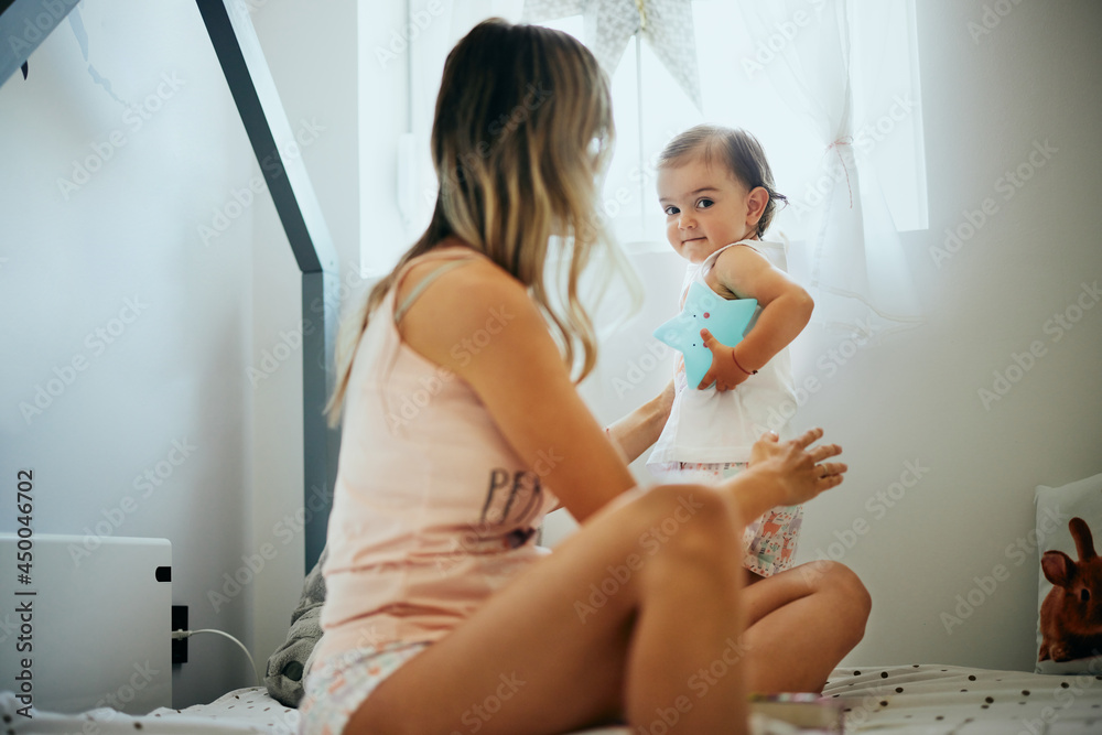Fototapeta premium Young beautiful mother playing with her beloved baby girl at home.