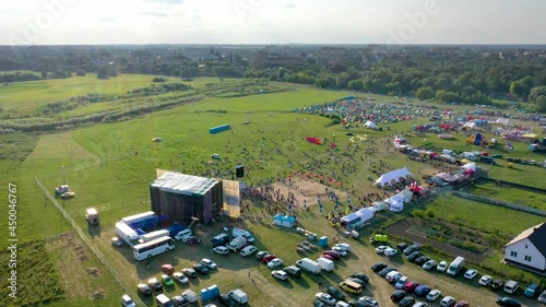 A drone flies over the stage surrounded by many people against the backdrop of the forest and the city
