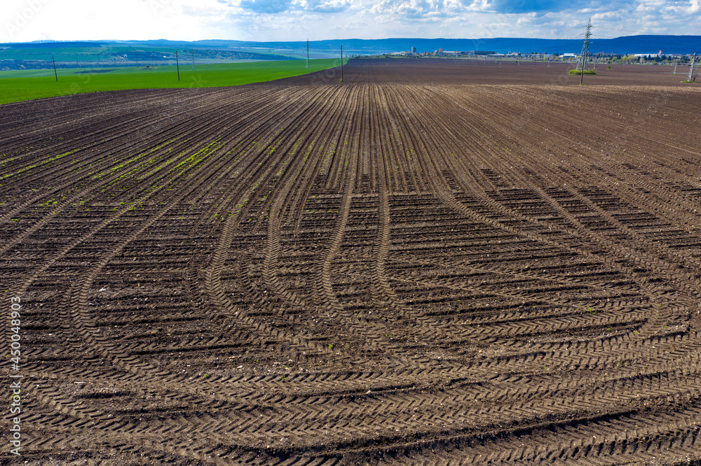 Rows of soil after plowing with traces of tires. Horizontal view with perspective. Rows of soil after plowing with traces of tires. Horizontal view with perspective.