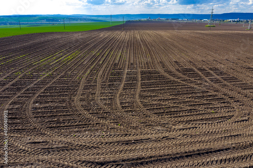 Rows of soil after plowing with traces of tires. Horizontal view with perspective.