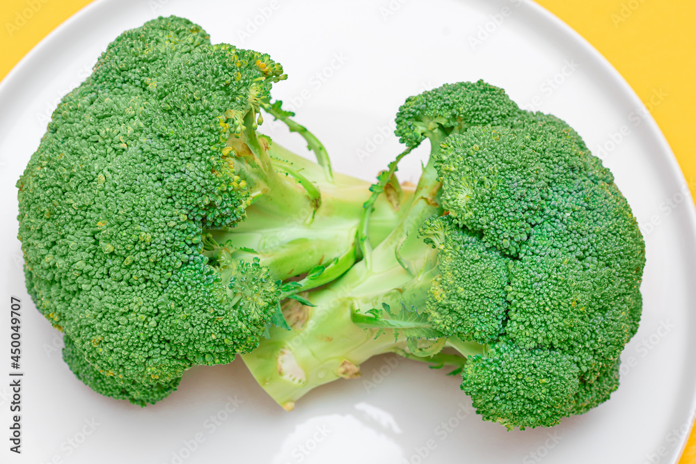 Two Fresh and Raw Pieces of Broccoli on White Plate. Uncooked Green Cabbage. Vegan and Vegetarian Culture. Raw Food. Healthy Eating and Vegetable Diet Two Fresh and Raw Pieces of Broccoli on White Plate. Uncooked Green Cabbage. Vegan and Vegetarian Culture. Raw Food. Healthy Eating and Vegetable Diet