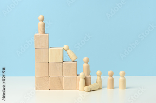 stairs from wooden cubes and a crowd of fallen wooden figures of men on a blue background.