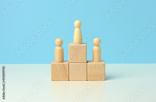 wooden figures of men stand on a pedestal of their cubes on a blue background