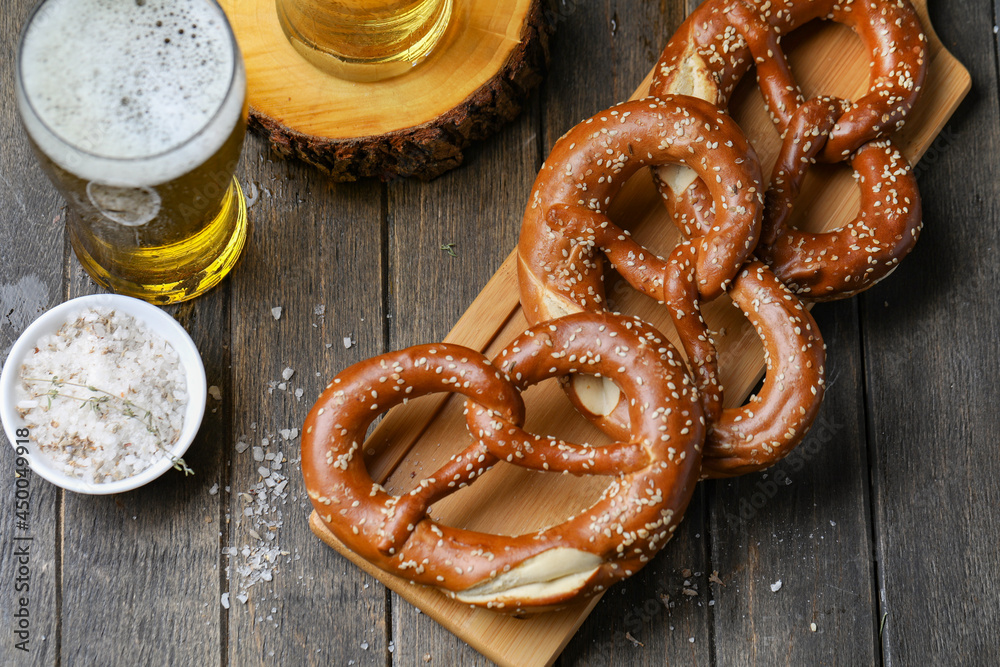 Traditional Pretzels With Salt And Sesame Seeds And Golden Beer In Glass On Wooden Background. Traditional Pretzels With Salt And Sesame Seeds And Golden Beer In Glass On Wooden Background.