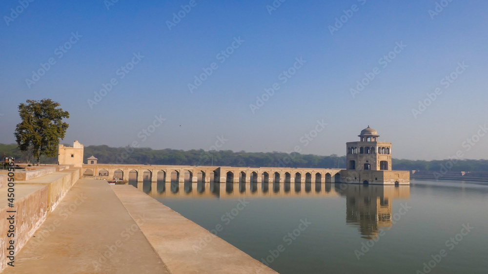 Early morning view of beautiful octagonal pavilion and stone bridge on water tank pool at mughal era Hiran Minar complex in Sheikhupura, Punjab, Pakistan