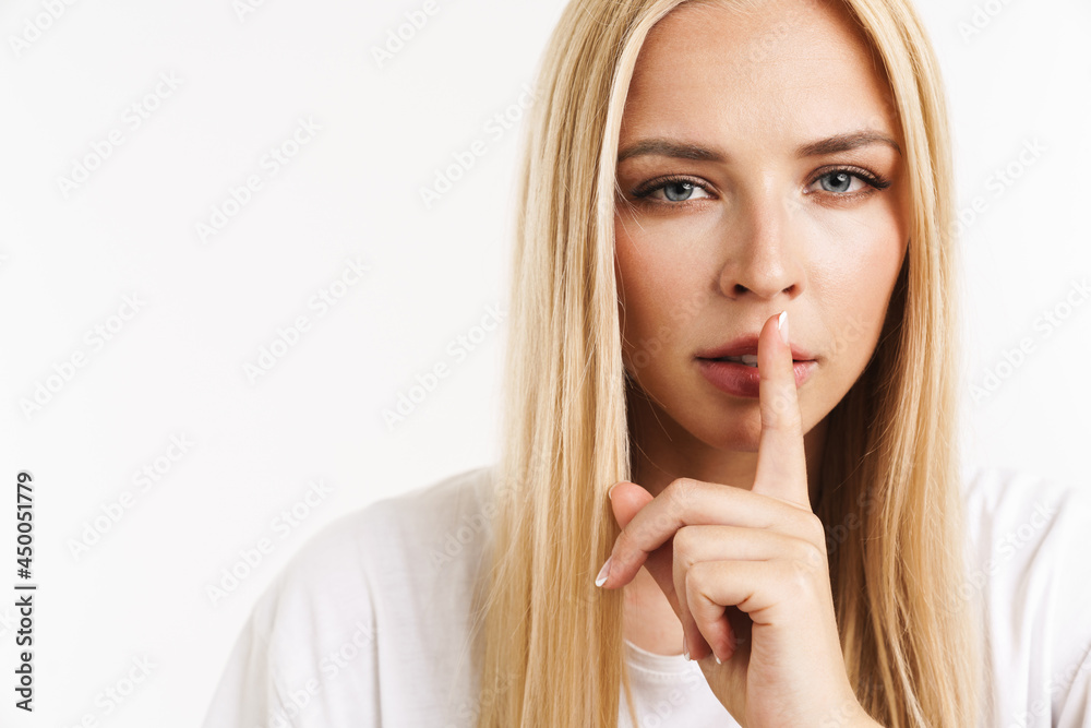 Young blonde woman in t-shirt showing silence gesture at camera Young blonde woman in t-shirt showing silence gesture at camera