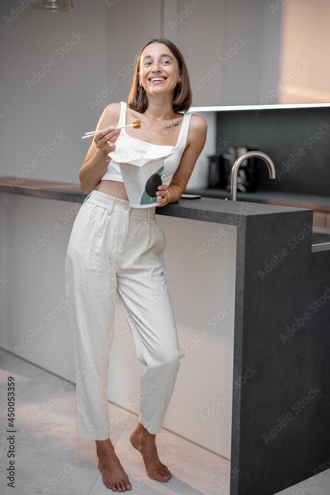 Portrait of a happy young woman with asian takeaway food on the modern kitchen at home. Ordering food home, healthy and modern lifestyle at kitchen