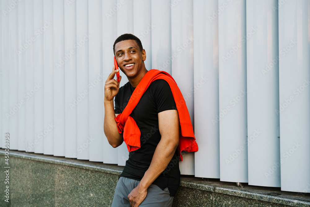 Black young man smiling while talking on cellphone Black young man smiling while talking on cellphone