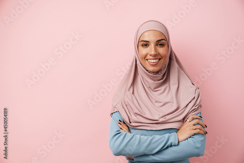 Canvas Print A smiling muslim woman wearing pink hijab standing with crossed arms