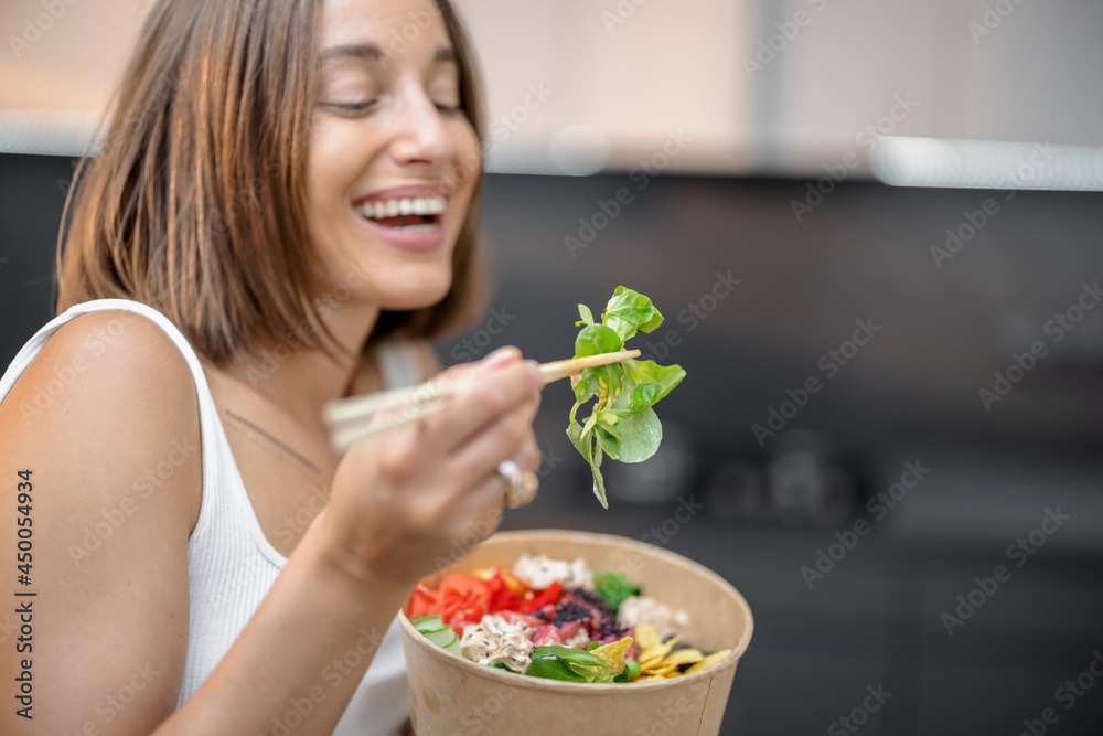 Young woman eating healthy asian bowl with tuna and salad on the modern kitchen at home. Healthy takeaway asian food and modern lifestyle at home Young woman eating healthy asian bowl with tuna and salad on the modern kitchen at home. Healthy takeaway asian food and modern lifestyle at home