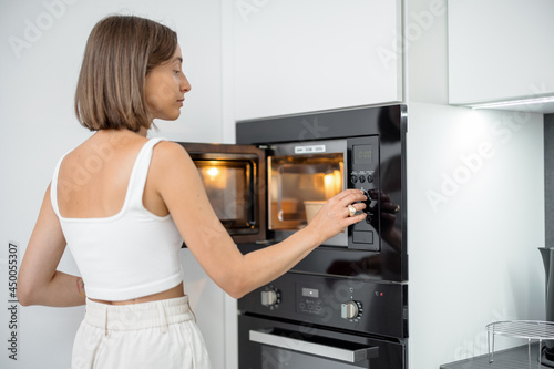 Photography Woman heating food with microwave machine at home, female using modern kitchen a