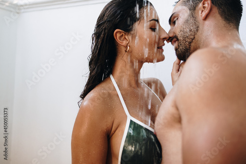 Romantic young couple kissing under the shower