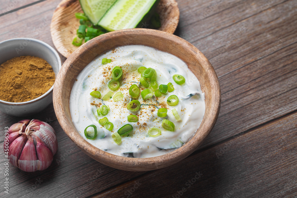 Traditional Indian Raita with Dahi in a bowl on a wooden table Traditional Indian Raita with Dahi in a bowl on a wooden table