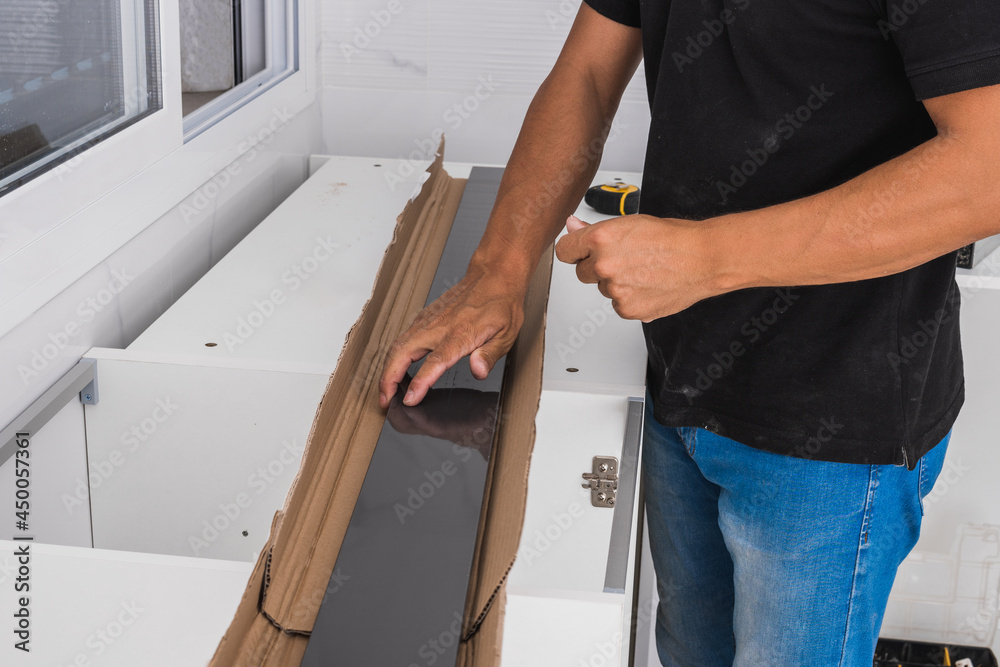 Man with black pieces of a cabinet ready to be assembled Man with black pieces of a cabinet ready to be assembled