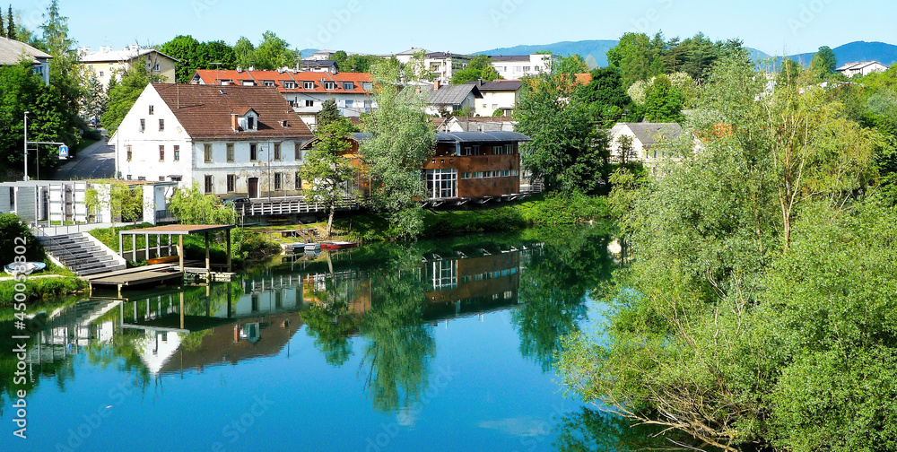 Fototapeta premium Novo Mesto, Slovenia - May 9. 2017: View over river Krka on village against summer sky